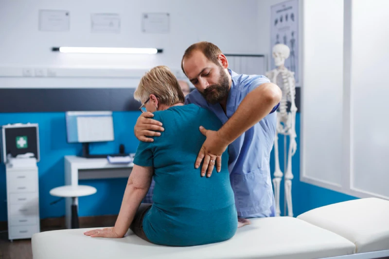 A professional chiropractor in Vancouver performing a back adjustment on an elderly female patient in a clinic.